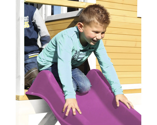Un garçon glisse sur un toboggan en plastique d''une aire de jeux.