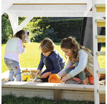 Drei Kinder spielen in einem Sandkasten mit Überdachung im Garten.