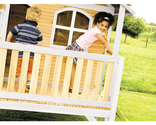 Des enfants jouent dans une cabane en bois avec toboggan dans le jardin.