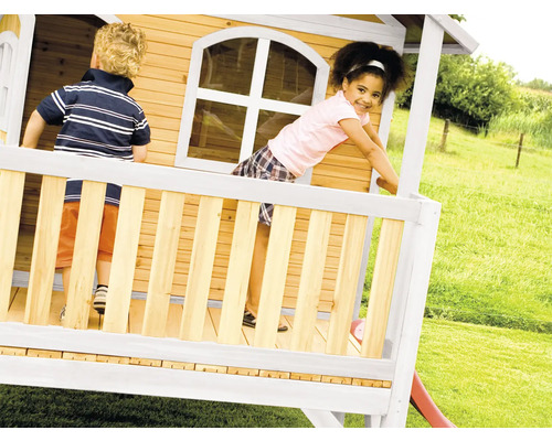 Des enfants jouent dans une cabane en bois avec toboggan dans le jardin.
