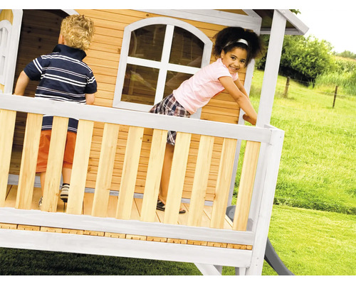 Des enfants jouent dans une cabane en bois avec toboggan dans le jardin.