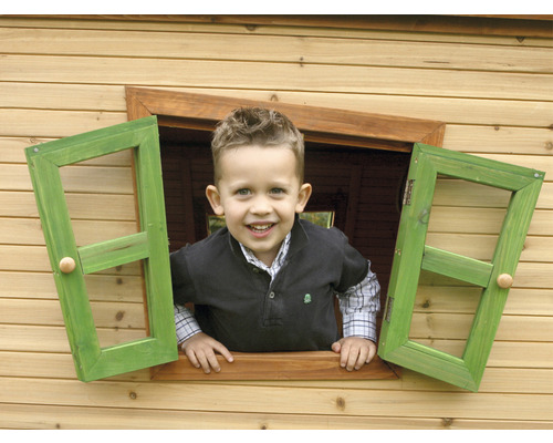 Un enfant regarde par la fenêtre d''une cabane en bois