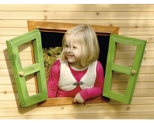 Une fillette blonde regarde par la fenêtre d''une cabane en bois.