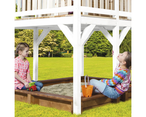 Deux enfants jouent dans un bac à sable sous une tour de jeu