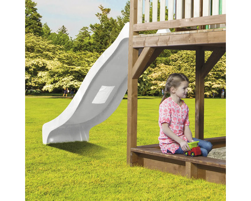 Tour de jeu avec toboggan et enfant jouant dans le jardin.
