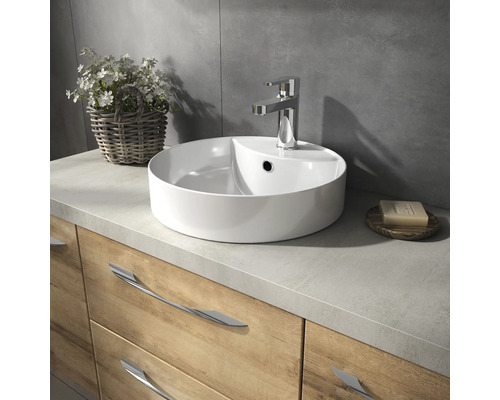 Vasque avec robinet, savon et décoration florale sur un meuble bas en bois