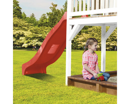 Aire de jeux avec toboggan rouge et bac à sable avec enfant jouant