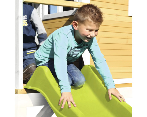 Kind rutscht auf einer Rutsche eines Spielhauses herunter.