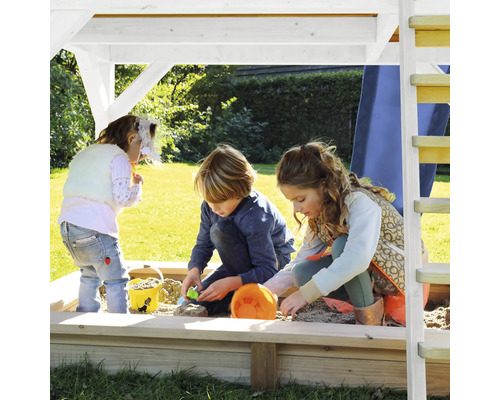 Des enfants jouent dans un bac à sable sous une tour de jeux