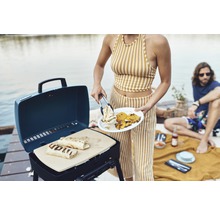 Une personne fait griller des wraps sur un barbecue à gaz portable à l''extérieur.