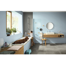 Salle de bains avec baignoire, lavabo, miroir, serviettes et un garçon lavant un chien dans la baignoire.