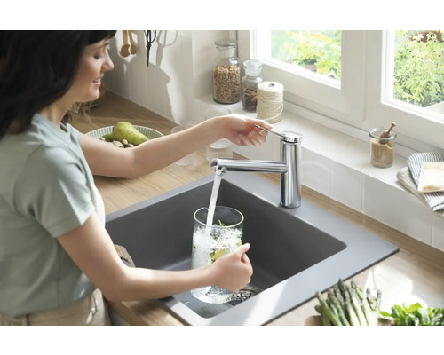 Femme remplissant un verre d''eau au lavabo avec robinet dans la cuisine