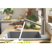 Küchenspüle mit Wasserhahn und laufendem Wasser in einer hellen Küche.