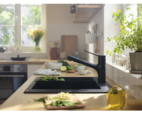 Scène de cuisine avec évier, robinet et ingrédients frais sur un plan de travail en bois.