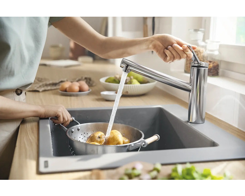 Femme lave des pommes de terre dans une passoire de cuisine sous un robinet