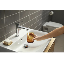 Salle de bains moderne avec vasque à poser, robinet et personne remplissant un verre d''eau