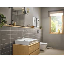 Salle de bains lumineuse avec lavabo, miroir, toilettes et fenêtre pour une ambiance conviviale