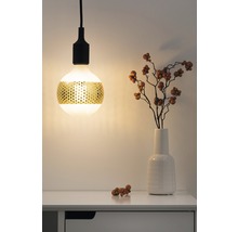 Lampe suspendue décorative avec motif perforé doré au-dessus d''une table