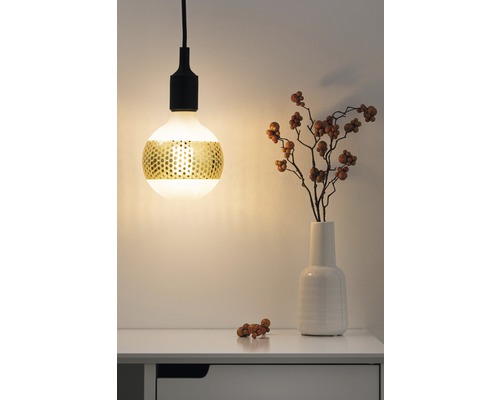 Dekorative Pendelleuchte mit goldfarbenem Lochmuster über einem Tisch