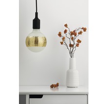 Suspension décorative avec motif doré à côté d''un vase avec des branches sur une table