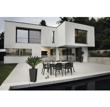 Modernes Haus mit Terrasse, Gartentisch und Stühlen.