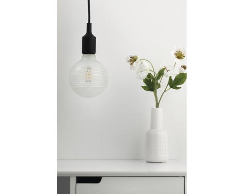 Dekorative Lampe neben einer Vase mit Blumen auf einem Tisch
