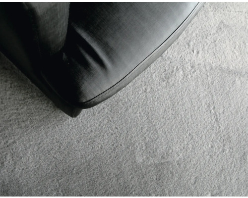 Detailaufnahme eines grauen Teppichs neben einem Möbelstück