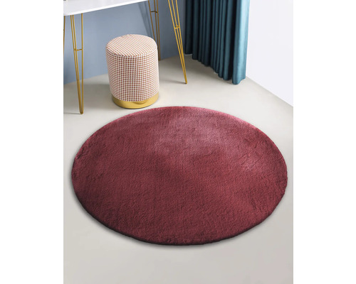 Runder Teppich aus Kunstfell im Raum mit Hocker und Tisch