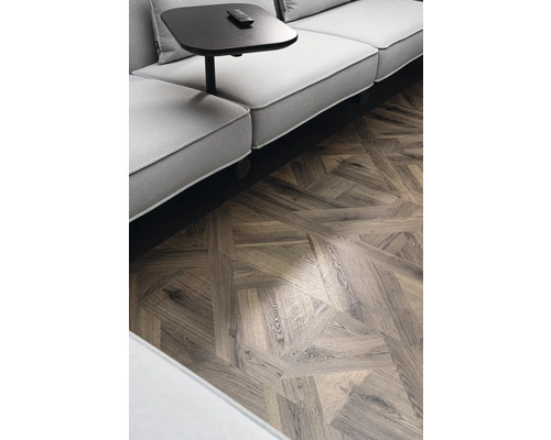 Gros plan d''une pièce avec un canapé, une table d''appoint et un parquet à chevrons.