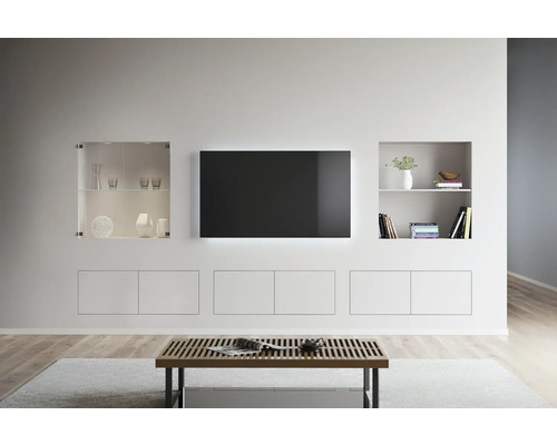 Aménagement de salon lumineux avec télévision, étagères et table basse.