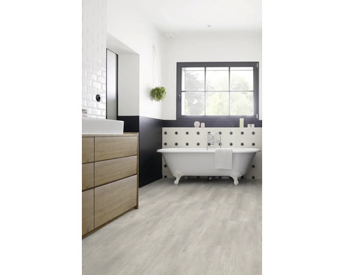 Salle de bains lumineuse avec baignoire îlot, meuble-lavabo et plancher en bois clair