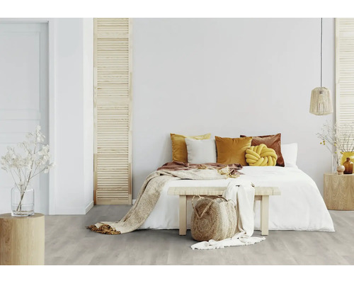 Chambre claire avec lit, coussins et plancher en bois