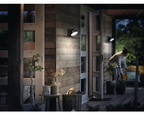 Aussenbereich mit Holzfassade, beleuchtet mit Wandleuchten.