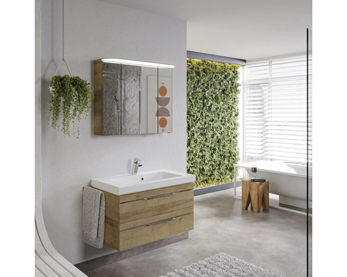 Salle de bains lumineuse avec meuble sous-lavabo, armoire de toilette, baignoire et mur végétal pour une atmosphère conviviale.