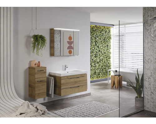 Salle de bain lumineuse avec lavabo, armoire de toilette et armoire latérale en aspect bois, complétée par des touches de vert
