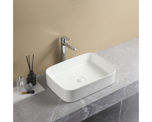 Vasque à poser rectangulaire en céramique avec robinet sur un plan de toilette