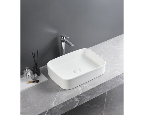 Vasque à poser rectangulaire en céramique avec robinetterie sur un plan de travail en marbre