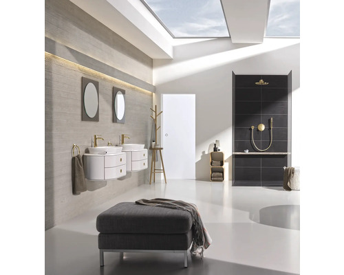 Badezimmer mit Waschtischen, Spiegeln, Dusche und Sitzhocker unter einem Dachfenster.