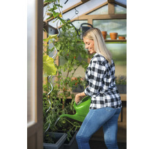 Femme arrosant des plantes dans une serre avec un arrosoir