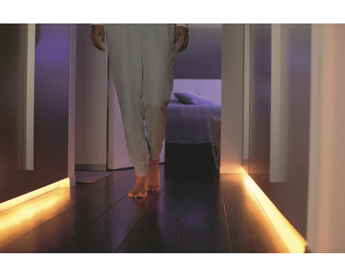 Personne marchant dans un couloir avec éclairage au sol.