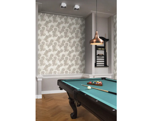 Une pièce avec un papier peint à motifs, une table de billard et une suspension.