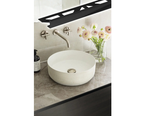 Salle de bains moderne avec vasque à poser, robinetterie, bouquet de fleurs et profilé LED