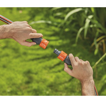 Deux mains connectent un raccord de tuyau d''arrosage.