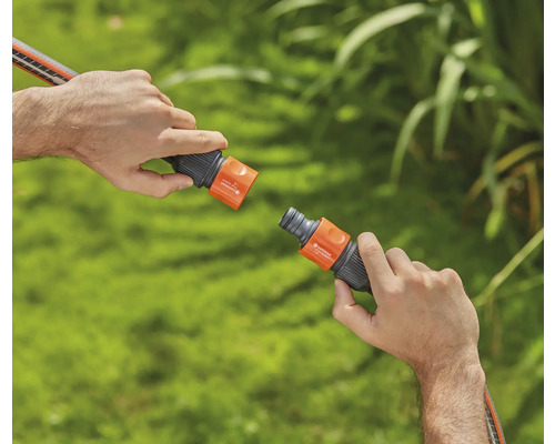 Deux mains connectent un raccord de tuyau d''arrosage.