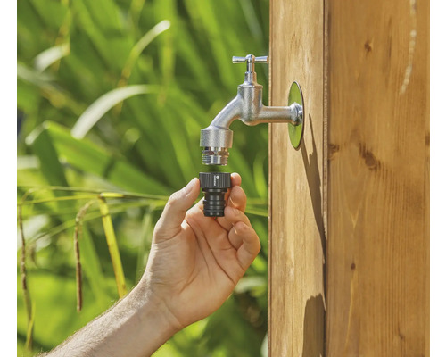 Hand schliesst Schlauchverbinder an Wasserhahn an