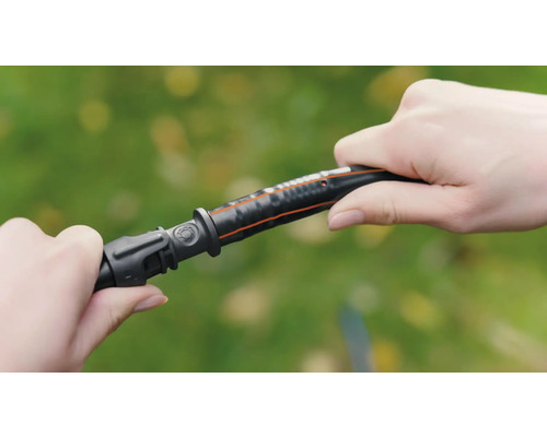 Une personne raccorde un élément de tuyau d''arrosage à un tuyau d''arrosage.