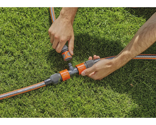 Scène d''arrosage de jardin avec raccord en T et raccords de tuyau sur gazon