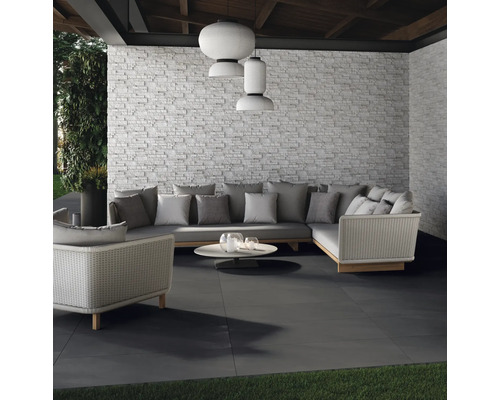 Terrasse mit Steinfliesen, Sitzgruppe und dekorativer Wand