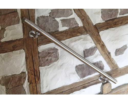 Main courante en acier inoxydable sur un mur avec des pierres et des poutres en bois