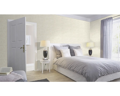 Chambre lumineuse avec lit, table de chevet, lampe et papier peint à motif de briques